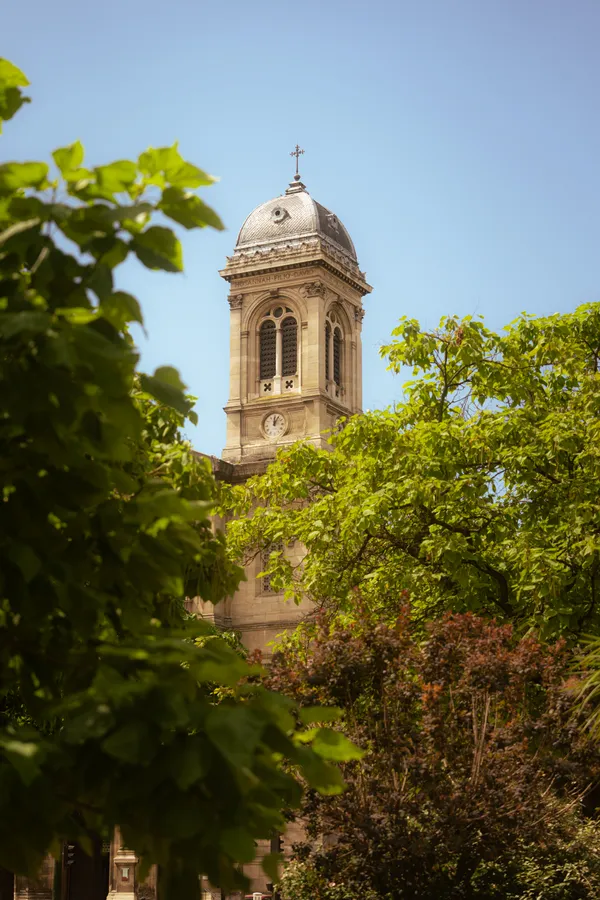 A historic tower framed by green leaves beneath a blue sky