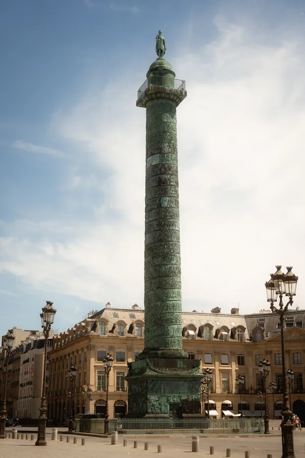 A column topped by a statue in a square surrounded by historic buildings