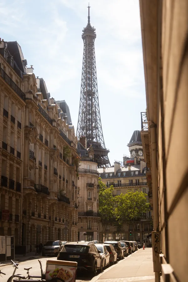 The Eiffel Tower above a Paris street, framed by surrounding buildings