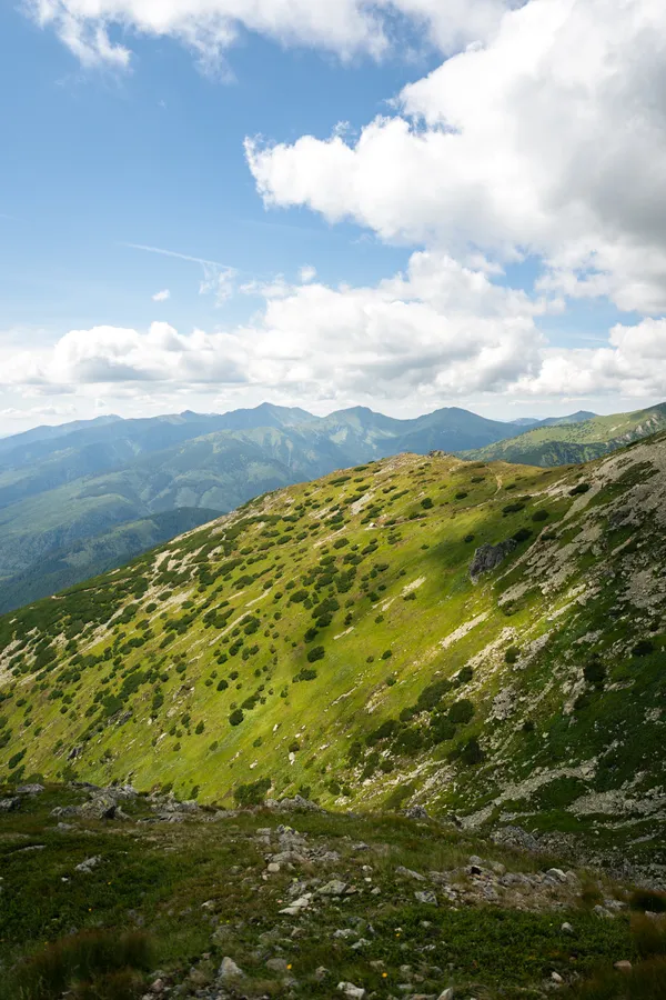 Green mountain slopes and distant ridges beneath a cloud-filled sky