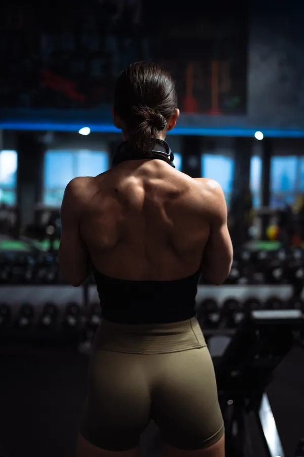 A person wearing headphones, photographed from behind in a gym
