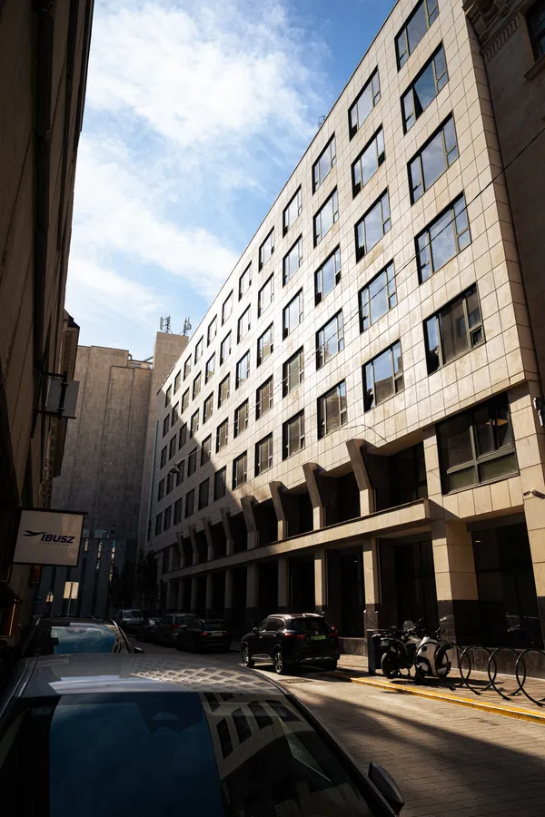 A sunlit modern building on a narrow city street