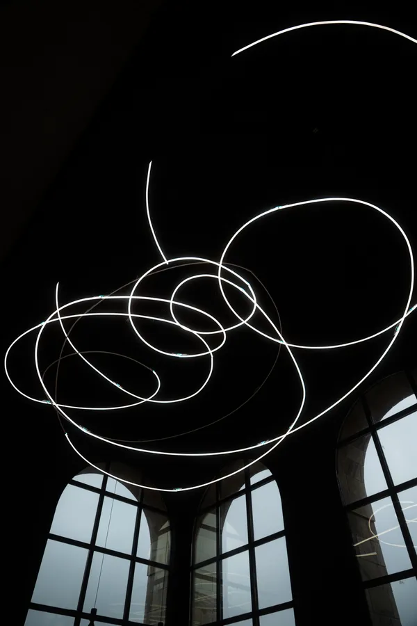Circular lights beneath a dark ceiling above tall windows