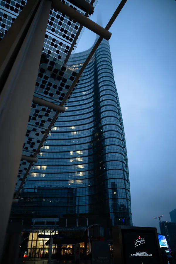 A high-rise building at dusk, framed by a metal structure