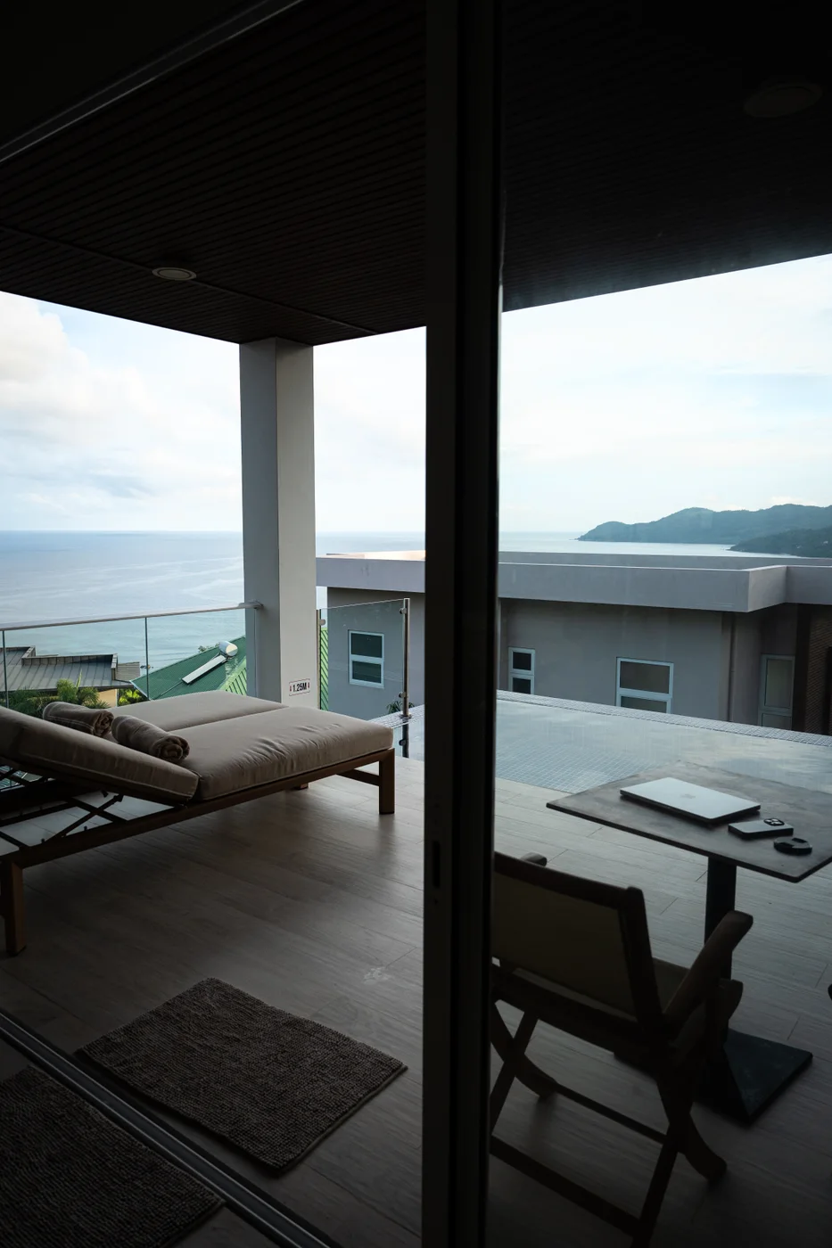 A view through glass doors towards a terrace and the sea
