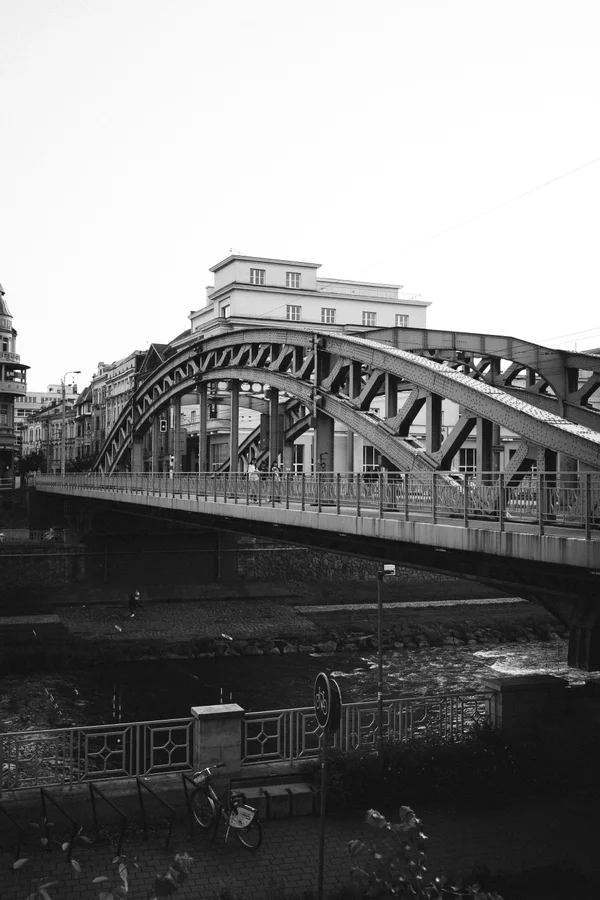 A black-and-white view of a steel arch bridge above a river